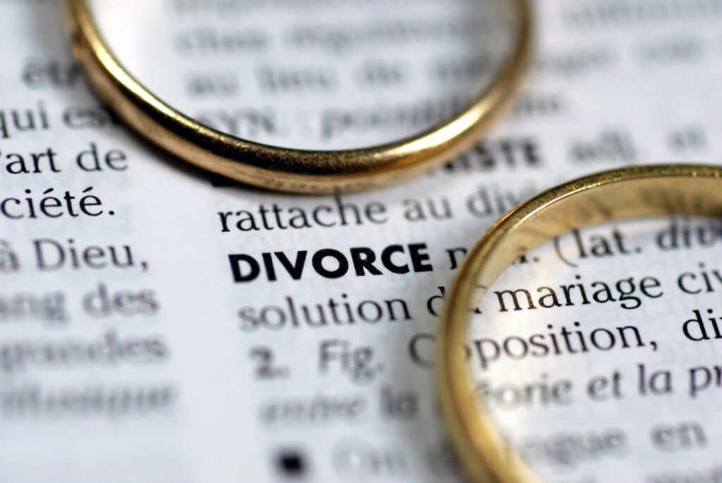 two gold rings on top of a dictionary page displaying the definition for divorce