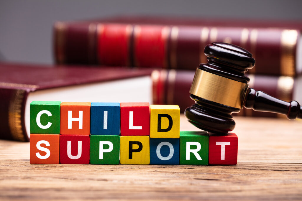A judge’s gavel resting on colorful blocks that spell out the phrase “child support.”