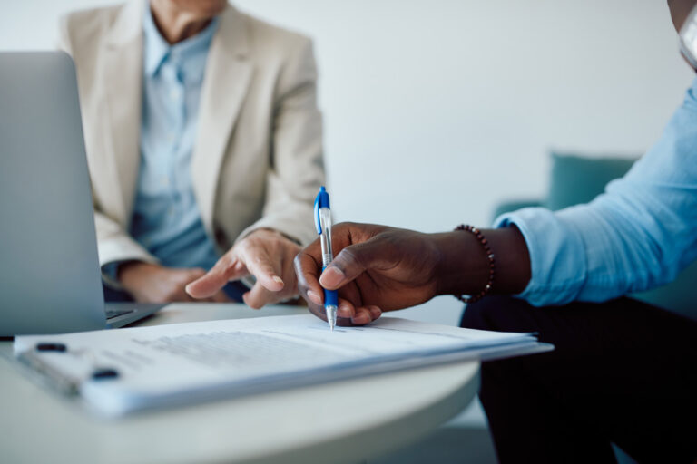 Two people reviewing insurance paperwork at a desk.