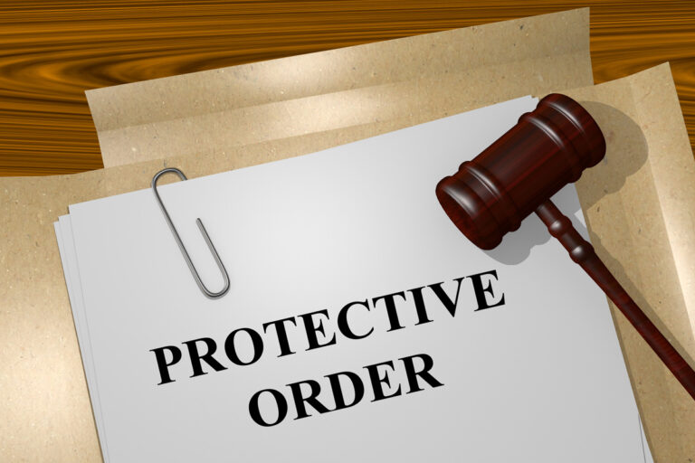 A piece of paper that says “PROTECTIVE ORDER” with a wooden gavel on top of it.